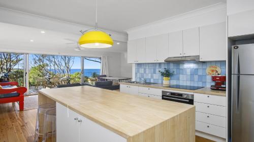 a kitchen with white cabinets and a yellow light fixture at Beach Bay and Bush at Killcare in Killcare