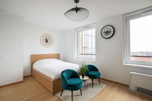 - une chambre avec un lit, deux chaises et une horloge dans l'établissement A L'Horizon - Joli Studio dans Strasbourg, à Strasbourg