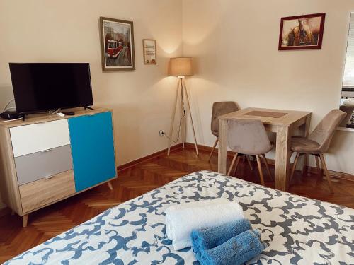 sypialnia z łóżkiem, telewizorem i stołem w obiekcie Cozy Trg w mieście Lazarevac