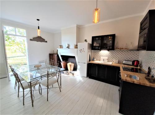 a kitchen with a glass table and a dining room at La Chartreuse d'Ertan "Les maîtres" 4 étoiles in Saint-Christophe-des-Bardes