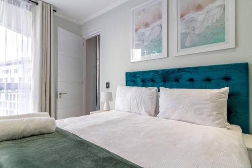 a bedroom with a large bed with a blue headboard at #AlimamaSpaces: Jay's Cassini in Midrand
