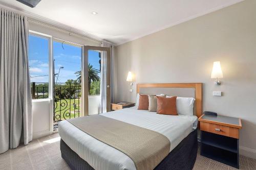 Quality Hotel Mildura Grand في ميلدورا: غرفه فندقيه بسرير وشرفه