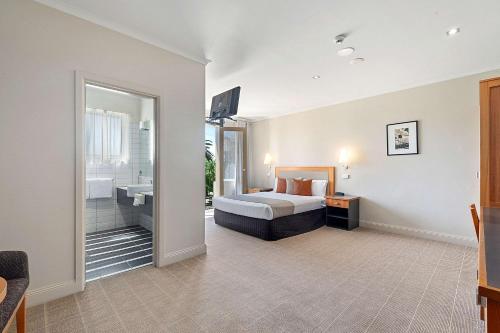 a bedroom with a bed and a bathroom with a sink at Quality Hotel Mildura Grand in Mildura