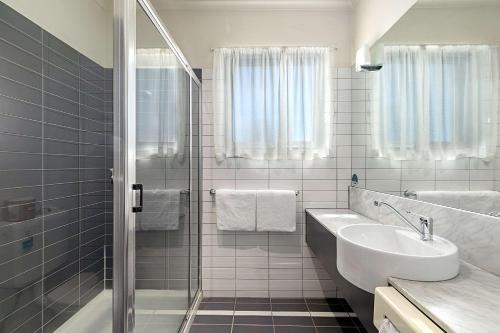 a white bathroom with a shower and a sink at Quality Hotel Mildura Grand in Mildura