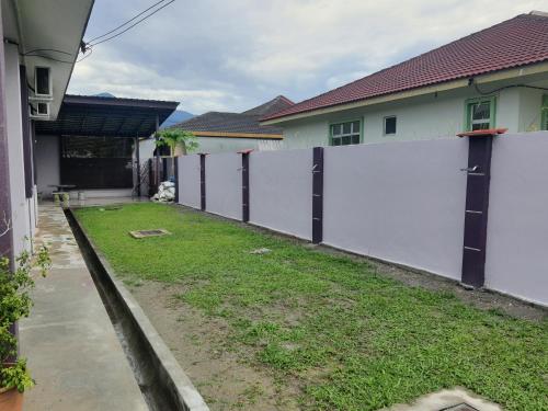 a white fence in front of a yard with houses at KS Villa Homestay KKB in Kampong Peruntun