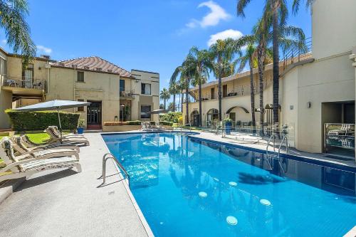 a large swimming pool with chairs and palm trees at Quality Hotel Mildura Grand in Mildura