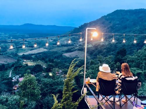 two people sitting at a table in chairs looking at a valley at Peace Zone เขาค้อ in Khao Kho