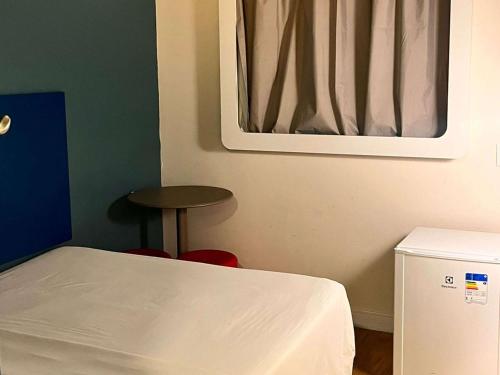 a room with a bed and a stool and a mirror at ibis budget Santos Gonzaga in Santos