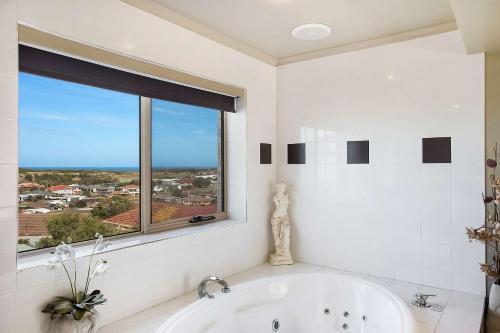 a white bathroom with a tub and a window at Comfort Inn On Raglan in Warrnambool