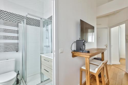 a bathroom with a toilet and a desk with a microwave at Charmant appartement à 10 minutes de la Défense in Suresnes