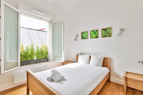 a white bedroom with a bed and a window at Charmant appartement à 10 minutes de la Défense in Suresnes