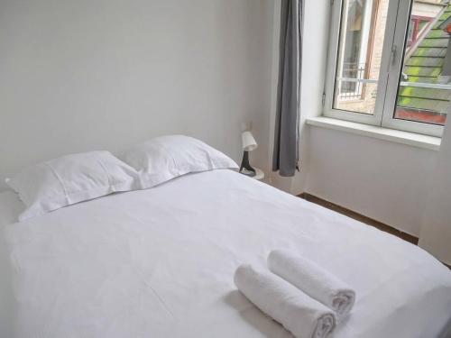 a white bed with two towels on it next to a window at Thiergarten - Charmant T2 à proximité de la gare in Strasbourg