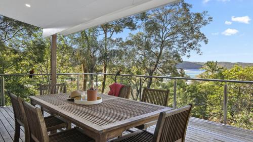 una mesa de madera en una terraza con vistas al océano en Bouddi Bush Retreat with Bay Views, en Booker Bay