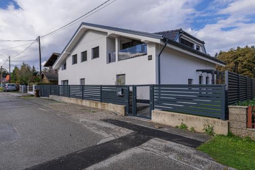 a white house with a black fence in front of it at Ski Apartments Frigo Pohorje 1 and 2 - Happy Rentals in Maribor