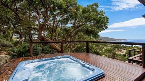 a jacuzzi tub on a wooden deck with trees at Atlas Beach House in Killcare
