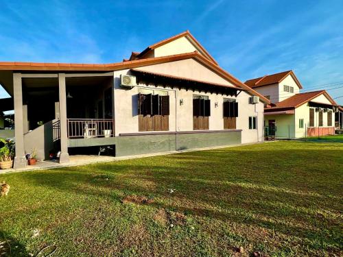 una casa con un prato verde davanti di Rumah Mok Aji Homestay Melaka a Malacca