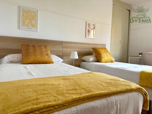 a hotel room with two beds with yellow sheets at Dos Torres Melkor - in Zaragoza