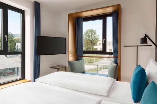 um quarto de hotel com duas camas e uma janela em Vienna House by Wyndham MQ Kronberg em Kronberg im Taunus