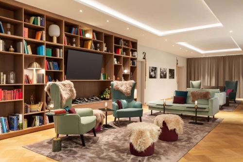 a living room with chairs and a tv and books at Vienna House by Wyndham MQ Kronberg in Kronberg im Taunus