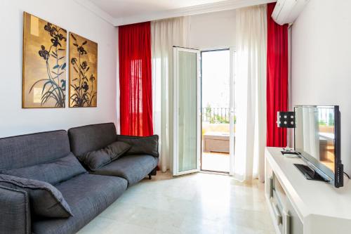 sala de estar con sofá y cortinas rojas en Abril Nerja, en Nerja
