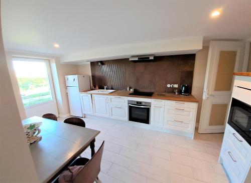 a kitchen with white cabinets and a table and a table and a tableablish at La Chartreuse d'Ertan "Les vignerons" 4 étoiles in Saint-Christophe-des-Bardes