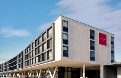 duży biały budynek z czerwonym napisem w obiekcie Leonardo Hotel Salzburg Airport w mieście Salzburg