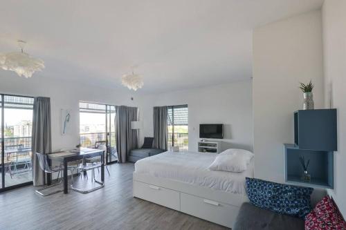 une chambre blanche avec un lit et un bureau dans l'établissement Bassin d'Austerlitz - Studio avec terrasse dans l'une des tours Black Swans, à Strasbourg