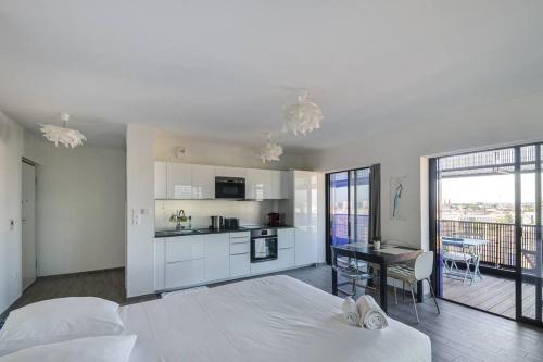 une chambre avec un grand lit blanc et une cuisine dans l'établissement Bassin d'Austerlitz - Studio avec terrasse dans l'une des tours Black Swans, à Strasbourg