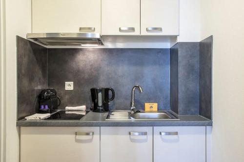 - une cuisine avec un évier et des placards blancs dans l'établissement Le 52 Zix - Joli studio au cœur de la Petite France, à Strasbourg