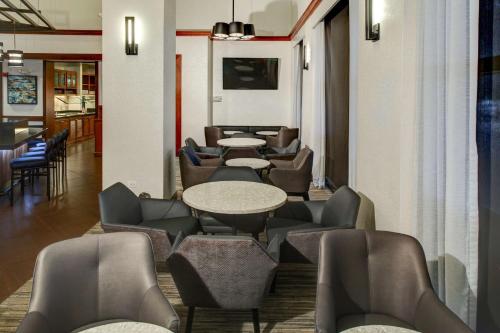 a waiting room with tables and chairs at Oklahoma City Airport Hotel & Suites Meridian Ave in Oklahoma City