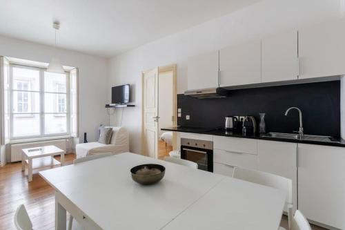 une cuisine avec un comptoir blanc et une table dans l'établissement Schlofa - Appt moderne dans Strasbourg, à Strasbourg