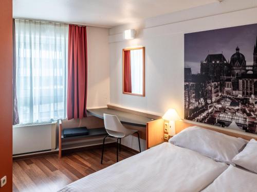 アーヘンにあるB&B Hotel Aachen-Hbfのベッドとデスクが備わるホテルルームです。