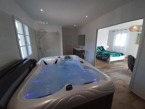 a large bath tub in a room with a bedroom at Villa Marguerite piscine et SPA privés in Mirabel