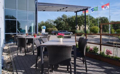 a patio with tables and chairs and a building at Holiday Inn Express Frankfurt Airport by IHG in Mörfelden-Walldorf