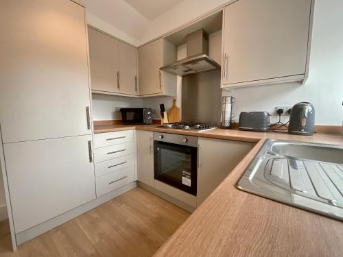a small kitchen with white cabinets and a sink at Rosie's Cottage - Beamish in Beamish