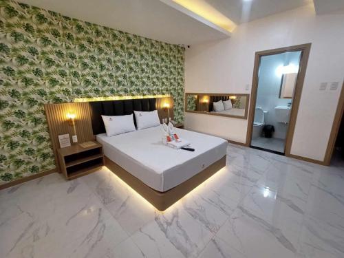 een slaapkamer met een groot wit bed en een spiegel bij Honey Hotel - Balibago in Angeles