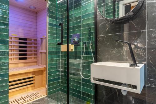 La salle de bains est pourvue d'une douche, d'un lavabo blanc et de carrelage vert. dans l'établissement Luxe Marais Getaway - Suite Exclusive avec Sauna, à Paris