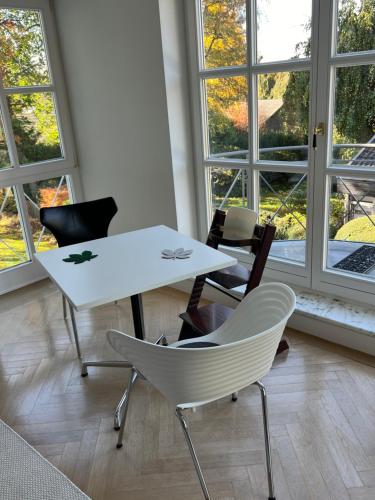 a white table and chairs in a room with windows at Herrenhaus - Starnberger See - Ammerland in Münsing am Starnberger See