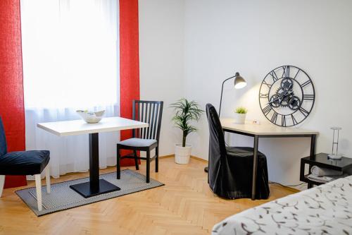 een woonkamer met een tafel en stoelen en een klok bij zimmer-graz in Graz