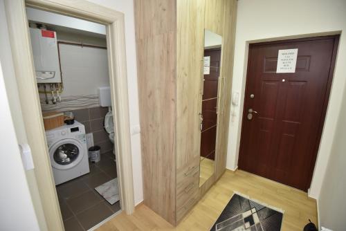 a hallway with a door to a bathroom with a washing machine at Studio 13 in Kragujevac