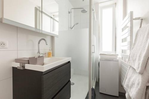 y baño blanco con lavabo y ducha. en Le 22 novembre - Appt en hypercentre, proche Place Kléber, en Estrasburgo