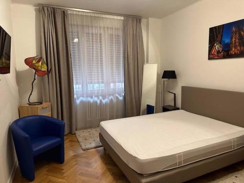 una camera con un letto, una sedia blu e una finestra di Le 22 novembre - Appt en hypercentre, proche Place Kléber a Strasburgo