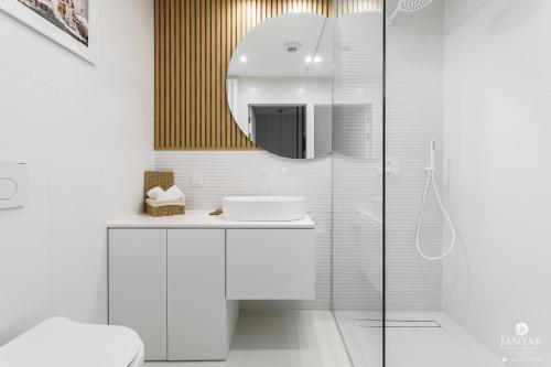 a white bathroom with a sink and a mirror at Shellter Apartments 117 J - by Jantar Apartamenty in Rogowo