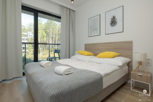 a bedroom with a large bed with yellow pillows at Shellter Apartments 117 J - by Jantar Apartamenty in Rogowo