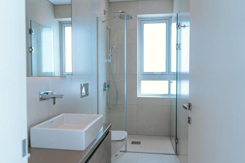 a white bathroom with a sink and a shower at Vivo Mare Beachfornt Villas - Azure in Ayia Napa