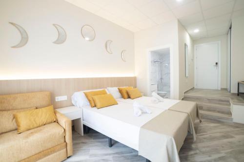a white bedroom with two beds and a couch at Hostal Altea Karma in Altea