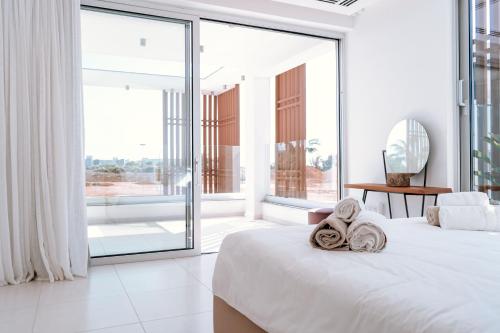 een witte slaapkamer met een groot raam en een bed bij Vivo Mare Beachfornt Villas - Azure in Ayia Napa