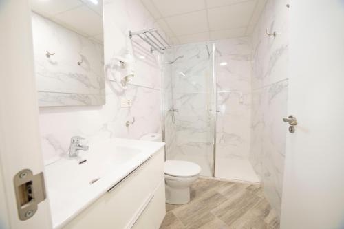 a white bathroom with a shower and a toilet at Hostal Altea Karma in Altea