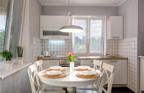 Apartmaji Koman في بليد: مطبخ مع طاولة بيضاء وكراسي ومطبخ مع دواليب بيضاء