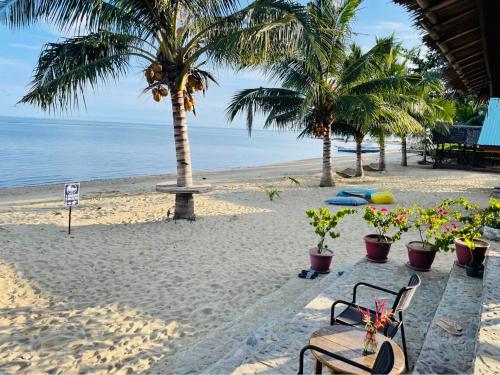 a beach with palm trees and a table and chairs at Mecaja Beach House in Roxas